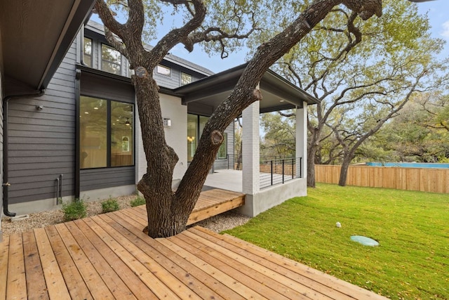 wooden terrace featuring a yard and fence