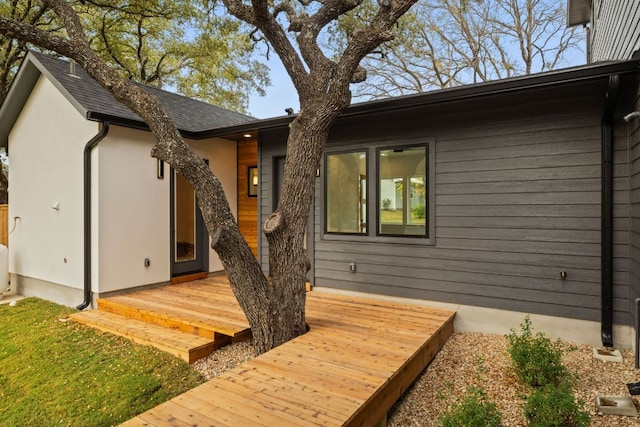 rear view of property featuring a deck and roof with shingles