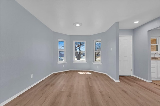 unfurnished room featuring light wood finished floors, a sink, and baseboards