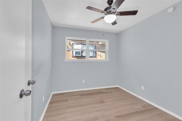 unfurnished room with ceiling fan, a textured ceiling, baseboards, and wood finished floors