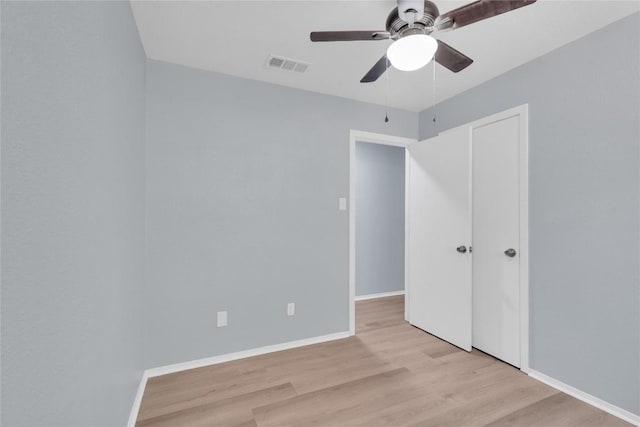 unfurnished bedroom featuring wood finished floors, a ceiling fan, visible vents, baseboards, and a closet