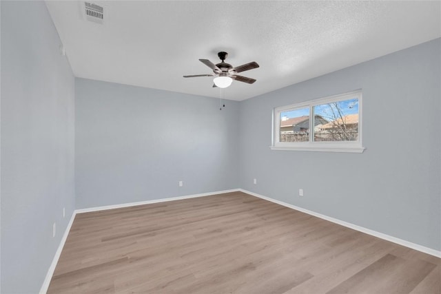 empty room with visible vents, baseboards, ceiling fan, wood finished floors, and a textured ceiling