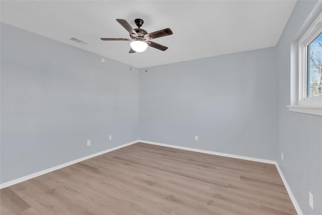 empty room with a ceiling fan, baseboards, visible vents, and light wood finished floors