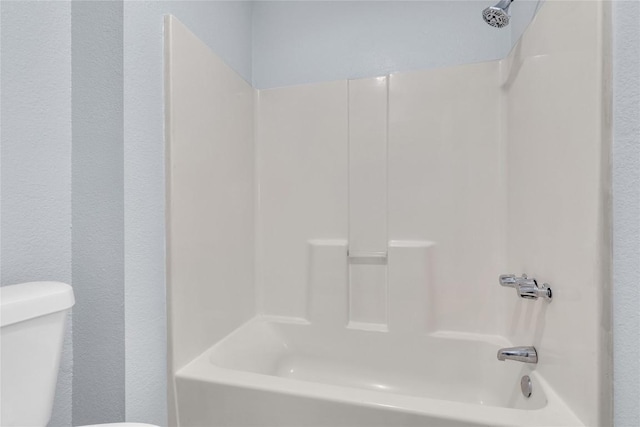 bathroom featuring shower / washtub combination and toilet