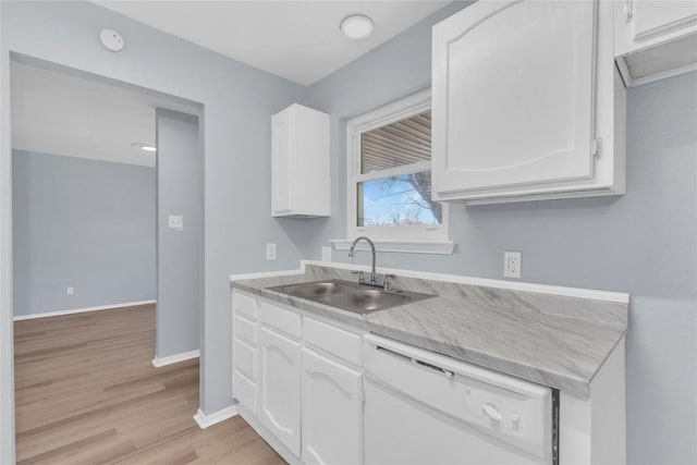 kitchen featuring light wood finished floors, white cabinetry, white dishwasher, a sink, and baseboards