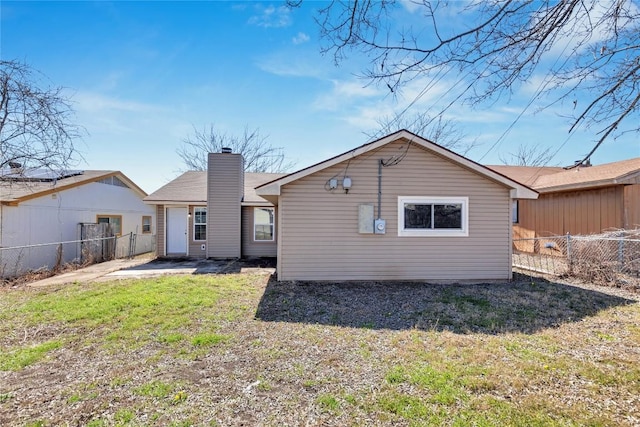 rear view of property featuring a fenced backyard, a chimney, and a yard