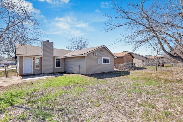 rear view of property featuring a yard, a chimney, and fence