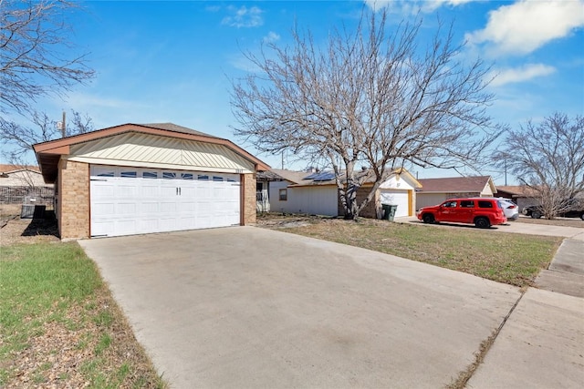 ranch-style home featuring a garage, roof mounted solar panels, brick siding, and driveway