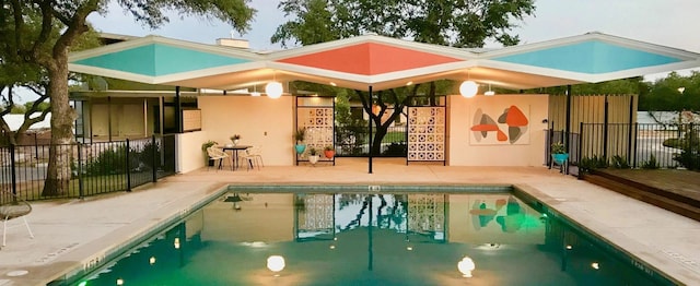 community pool with a patio area and fence