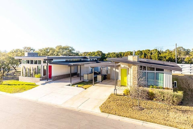 view of front of property featuring an attached carport, driveway, and solar panels