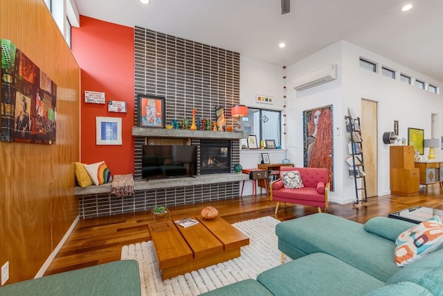 living area featuring recessed lighting, a fireplace, an AC wall unit, and wood finished floors