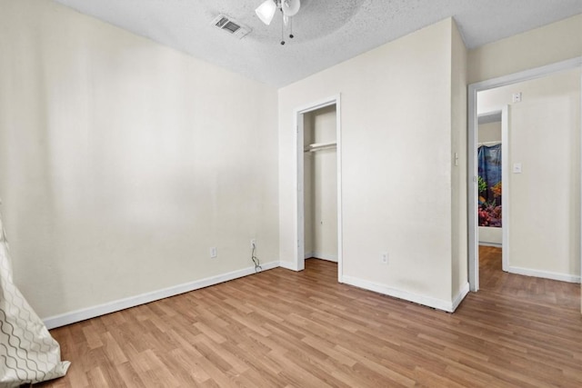 unfurnished bedroom with light wood-type flooring, baseboards, visible vents, and a textured ceiling