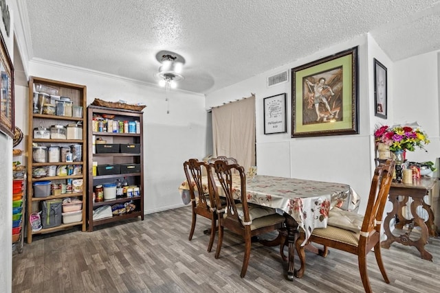 dining area featuring a textured ceiling, wood finished floors, and visible vents