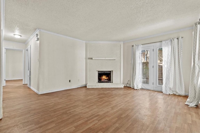 unfurnished living room with a brick fireplace, wood finished floors, and crown molding