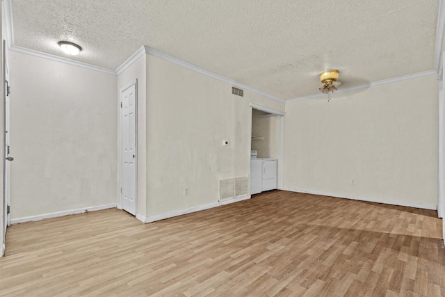 spare room featuring washing machine and dryer, visible vents, crown molding, and light wood finished floors