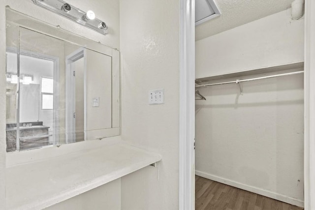 bathroom with a textured ceiling, baseboards, and wood finished floors