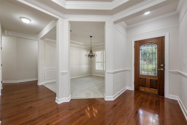 foyer featuring ornamental molding, a decorative wall, an inviting chandelier, and hardwood / wood-style flooring