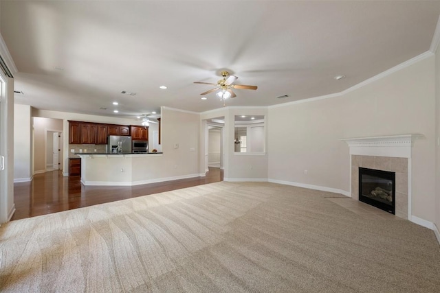 unfurnished living room featuring ornamental molding, a tile fireplace, a ceiling fan, and baseboards