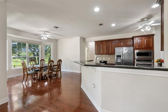 kitchen with visible vents, appliances with stainless steel finishes, decorative backsplash, and dark wood-type flooring