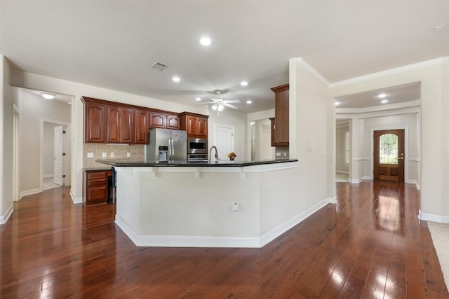 kitchen with dark wood finished floors, dark countertops, visible vents, appliances with stainless steel finishes, and a sink