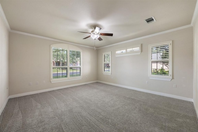 carpeted spare room featuring ornamental molding, plenty of natural light, visible vents, and baseboards