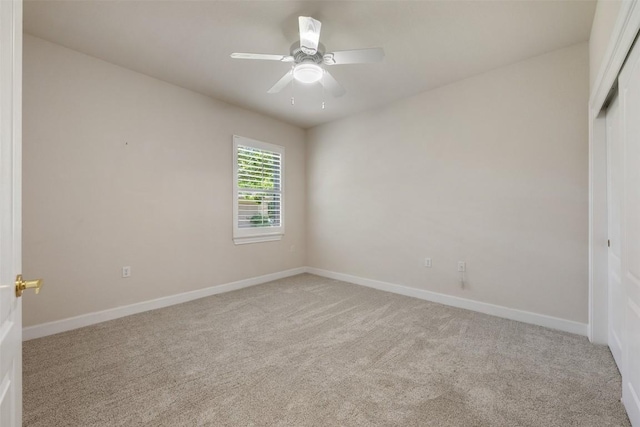 spare room with baseboards, a ceiling fan, and light colored carpet