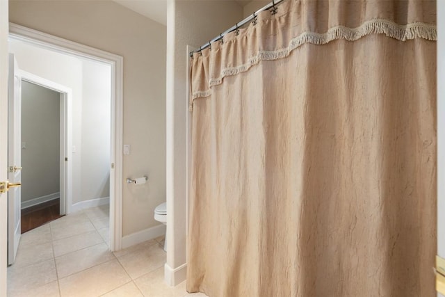 bathroom featuring toilet, baseboards, and tile patterned floors