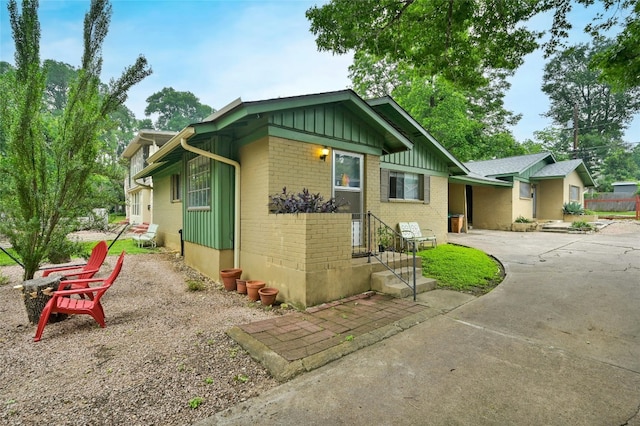 view of front of home with board and batten siding, concrete driveway, and brick siding