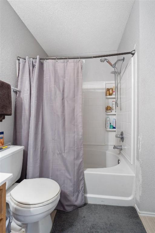 full bath featuring a textured ceiling, toilet, shower / bath combo, and vanity