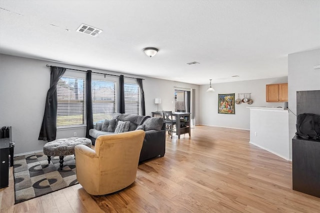 living area featuring light wood-style floors, baseboards, and visible vents