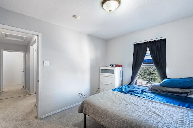 bedroom with baseboards, attic access, and light colored carpet