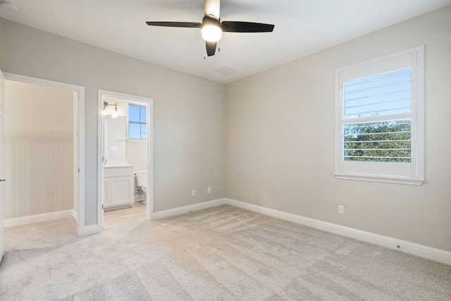 unfurnished bedroom with light carpet, ceiling fan, ensuite bath, and baseboards