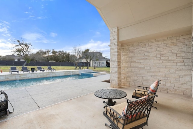 view of pool with a yard, a pool with connected hot tub, a patio, and fence