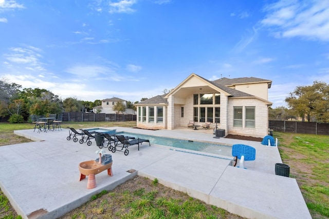 rear view of house featuring a patio, stone siding, a fenced backyard, and a fenced in pool