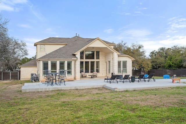 back of property with fence, a lawn, and a patio