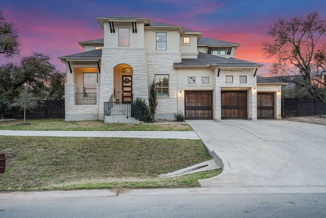 view of front facade featuring a garage, driveway, fence, and stucco siding