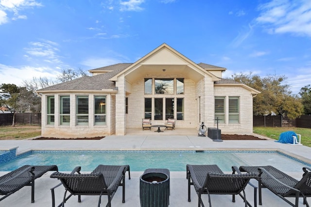 rear view of house with a shingled roof, a fenced in pool, a patio area, and fence