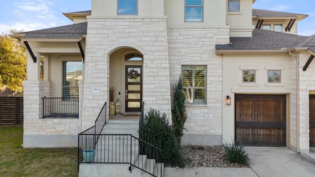 view of front of house with driveway, a shingled roof, fence, and stucco siding