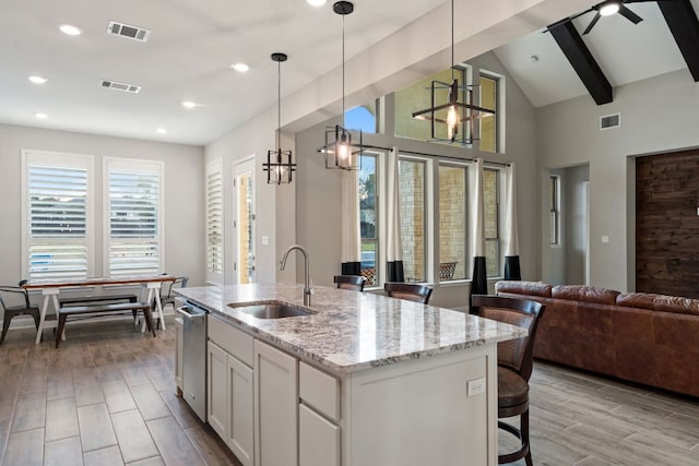 kitchen featuring visible vents, light stone counters, a sink, and open floor plan