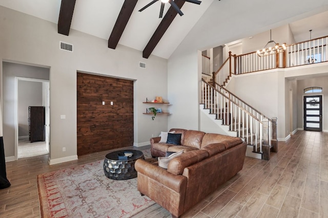 living room with stairs, beamed ceiling, wood finished floors, and visible vents