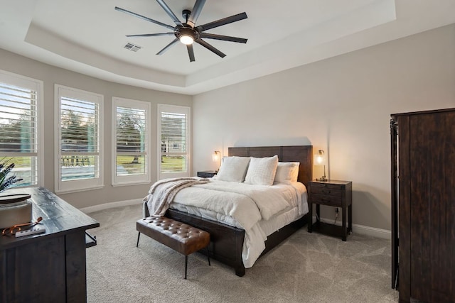 bedroom with ceiling fan, carpet floors, visible vents, baseboards, and a raised ceiling