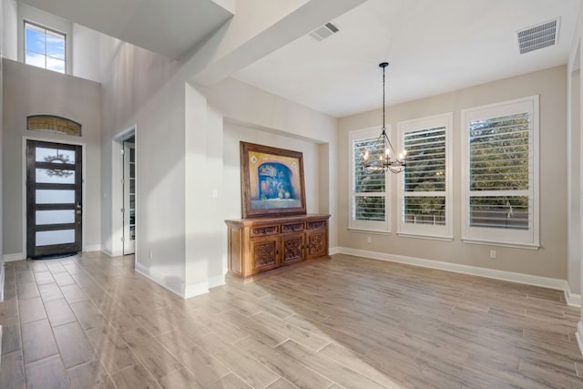 entrance foyer with a chandelier, light wood-style flooring, visible vents, and baseboards