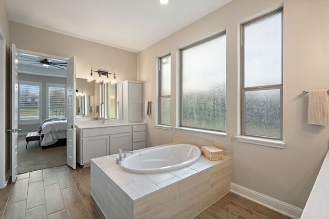 bathroom featuring wood finished floors, vanity, baseboards, a bath, and ensuite bath