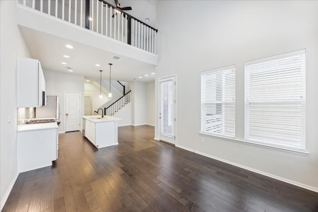 10204 Jacksboro Trl, Austin, TX 78717 - unfurnished living room with a sink, dark wood-style floors, a high ceiling, stairway, and baseboards