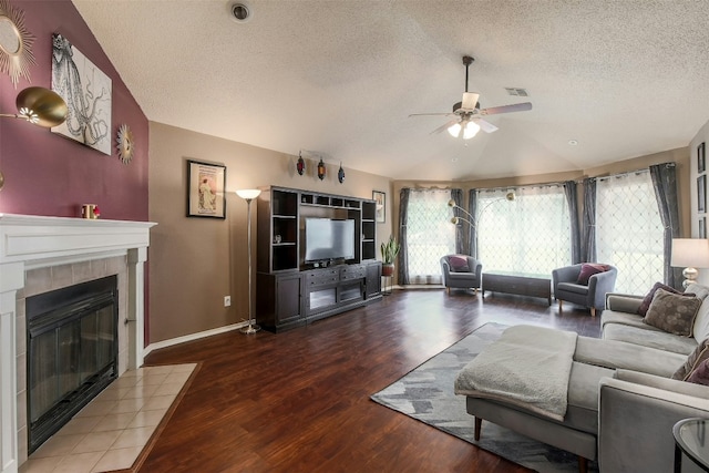 living area featuring a textured ceiling, lofted ceiling, a ceiling fan, wood finished floors, and a fireplace