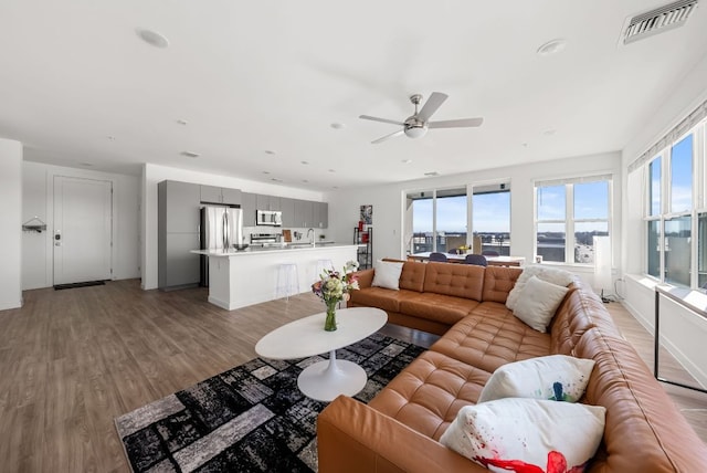 living area with light wood-style floors, ceiling fan, and visible vents