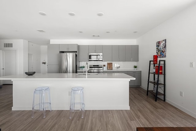 kitchen with a spacious island, light wood-style flooring, appliances with stainless steel finishes, gray cabinets, and light countertops