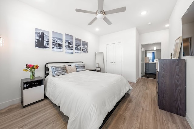 bedroom with ensuite bathroom, recessed lighting, light wood-style flooring, and baseboards