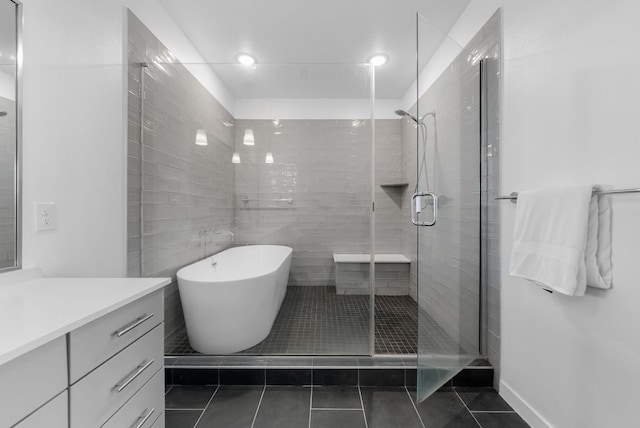 bathroom featuring a stall shower, vanity, a freestanding tub, and tile patterned floors