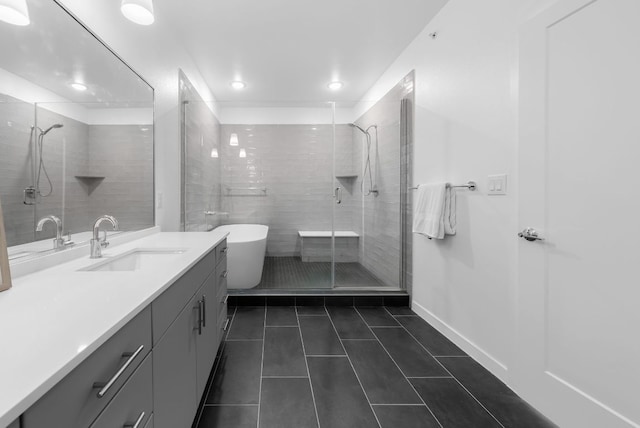 bathroom featuring tile patterned flooring, vanity, baseboards, a freestanding bath, and a stall shower